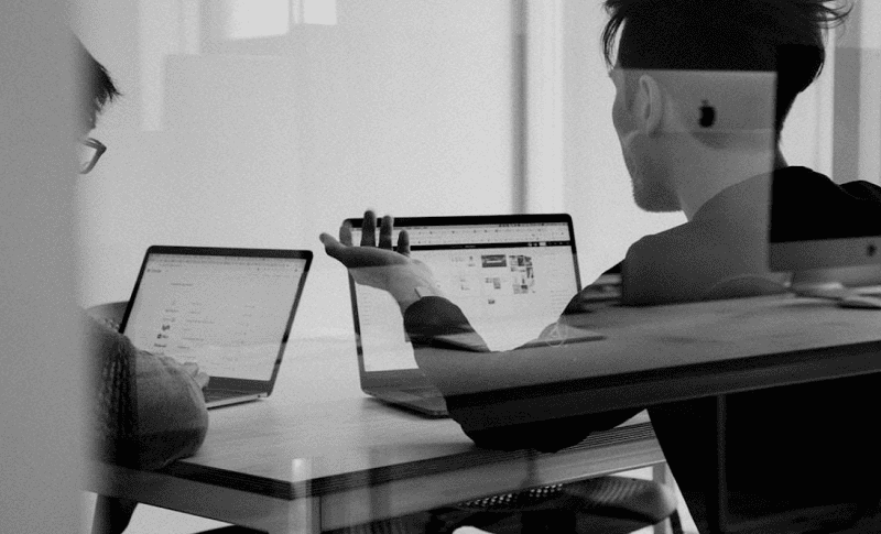 Two businessmen on their laptops choosing the best proposal software available